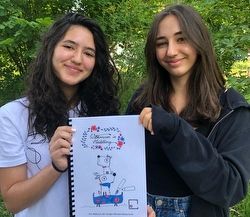 Schülerinnen zeigen Ihr Malbuch für Flüchtlingskinder
